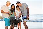 Smiling young friends having barbecue together on the beach