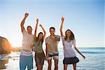 Cheerful group of friends dancing together on the beach