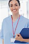 Smiling nurse holding files and looking at camera in medical office