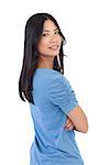 Smiling asian woman with arms crossed looking over her shoulder on white background