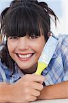 Pretty woman lying on floor holding paint brush smiling at camera