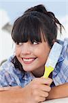 Cute woman lying on floor holding paint brush looking away