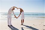Cute couple forming heart shape with arms at the beach