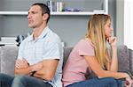 Couple sitting back to back after a fight on the couch in sitting room at home