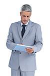 Frowning businessman using tablet pc on white background