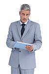 Serious businessman using tablet pc looking at camera on white background