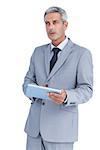 Serious businessman using tablet pc looking away on white background