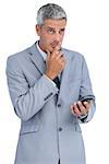 Worried businessman holding his cellphone against white background