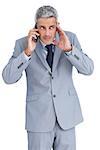 Attentive businessman answering phone against white background