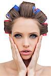 Sensual model with hair curlers touching her cheeks