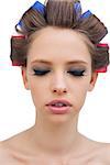 Pretty model with hair curlers closing eyes on white background