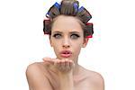 Young model in hair rollers blowing a kiss and looking at camera