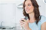 Radiant brunette drinking white wine in her kitchen