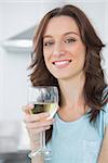 Brunette in her kitchen having a glass of white wine