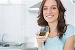 Pretty brunette in her kitchen having a glass of wine