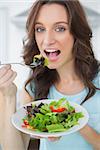 Healthy brunette having salad in her kitchen