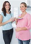 Smiling pregnant woman and her friend in the kitchen