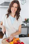 Pretty brunette cutting peppers in her kitchen