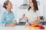 Brunette cooking while talking to her friend in her kitchen