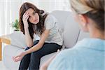 Worried woman sitting and looking at her therapist during a session