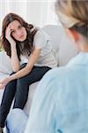 Upset woman sitting and looking at camera during therapy session in office