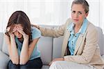 Worried woman being comforted by her understanding therapist and sitting on the couch