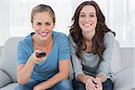 Cheerful women watching television  sitting on the sofa