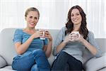 Friends having coffee while sitting on the sofa looking at camera