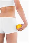 Toned female buttocks with orange on hand on white background