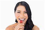 Gorgeous brown haired model eating strawberry on white background