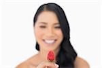 Attractive brown haired model holding strawberry on white background