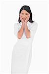 Elegant dark haired model wearing white dress touching her face on white background