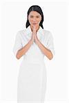 Elegant dark haired model with white dress joining hands on white background