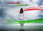 Businesswoman looking at red and green arrows in cloudy desert landscape