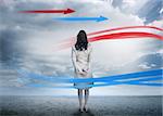 Businesswoman looking at red and blue arrows in cloudy desert landscape