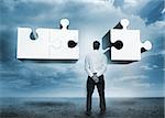 Businessman standing looking at jigsaw puzzle in cloudy desert setting