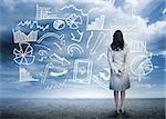Businesswoman standing looking at data flowchart in cloudy landscape