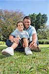 Attractive dad and son smiling into the camera in a park