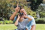 Dad and son looking at the sky with binoculars in the park on sunny day