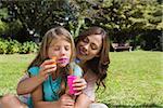 Daughter blowing bubbles with smiling mother in the park