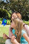 Mother with daughter blowing pinwheel in the park on summers day