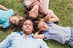 Sleeping family lying on the grass in a circle in the park