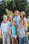 Happy family and grandparents in the countryside smiling at camera