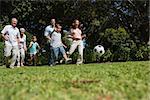Cheerful multi generation family playing football in the park