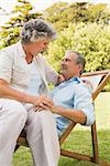 Happy mature couple sitting on sun lounger in park