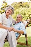 Smiling mature couple resting on sun lounger and looking at camera