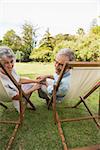 Smiling mature couple lying on sun loungers and looking at camera
