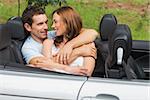 Couple in love cuddling in the backseat and chatting in convertible