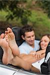 Happy couple cuddling in the backseat with focus on foot in a convertible