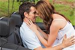 Young couple feeling romantic in back seat of convertible in countryside